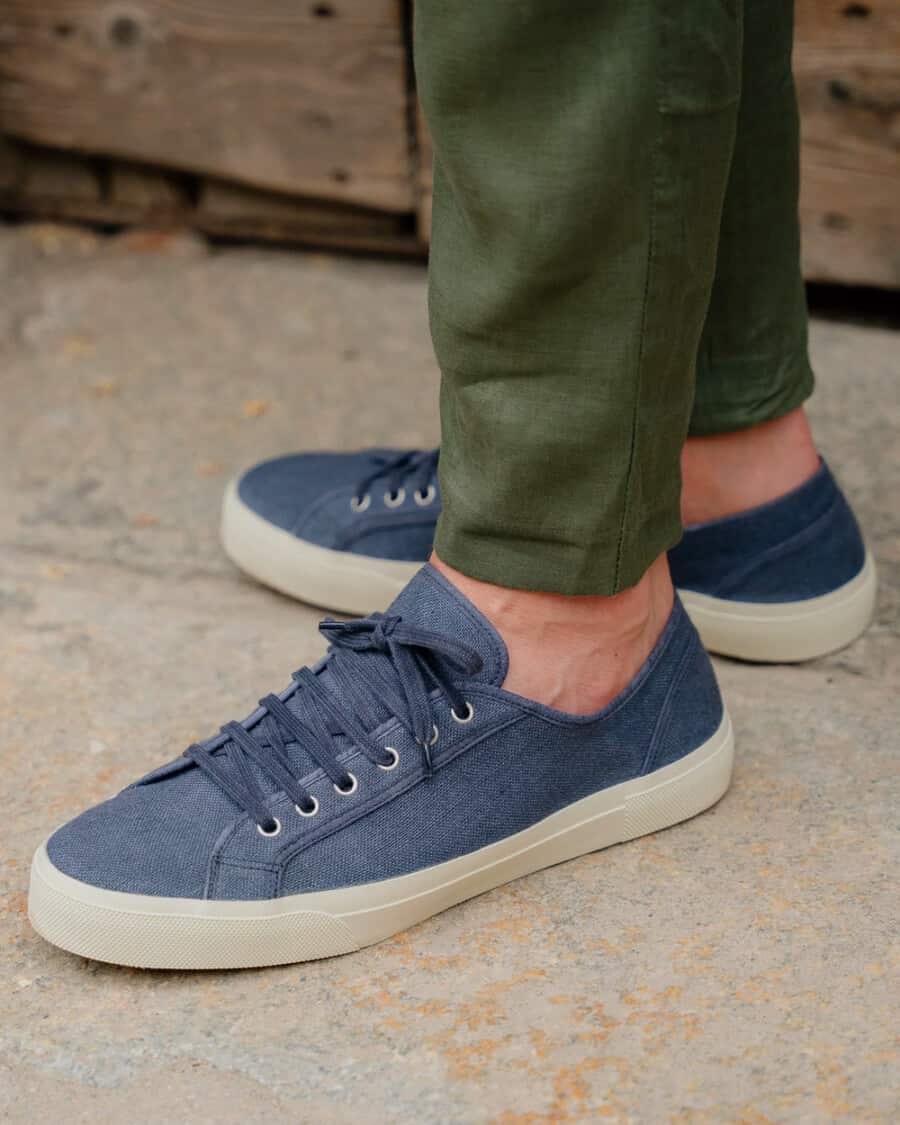 Men's Velasca blue linen plimsoll sneakers worn sockless on feet with green pants