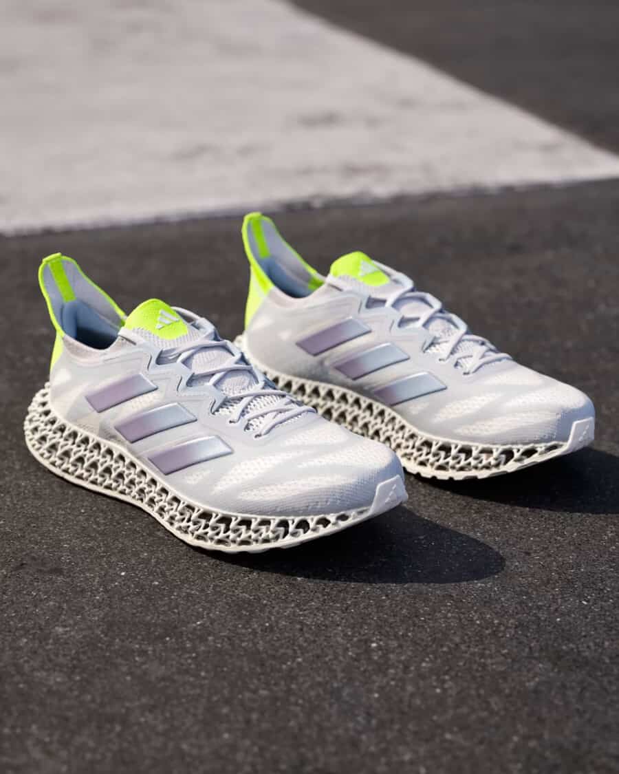 A pair of Adidas 4DFWD 3 Running Shoe sneakers in white and metallic grey set on asphalt 