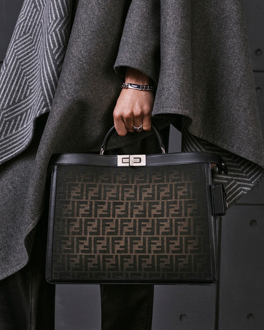 Man holding a branded Fendi black tote/briefcase bag