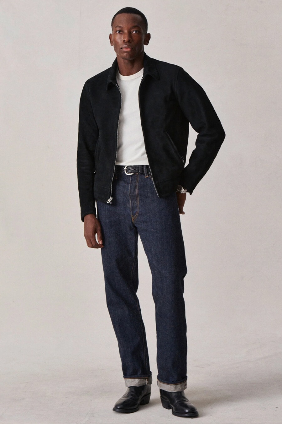 Men's raw denim selvage jeans, tucked in white T-shirt, navy suede Harrington jacket and black leather boots outfit