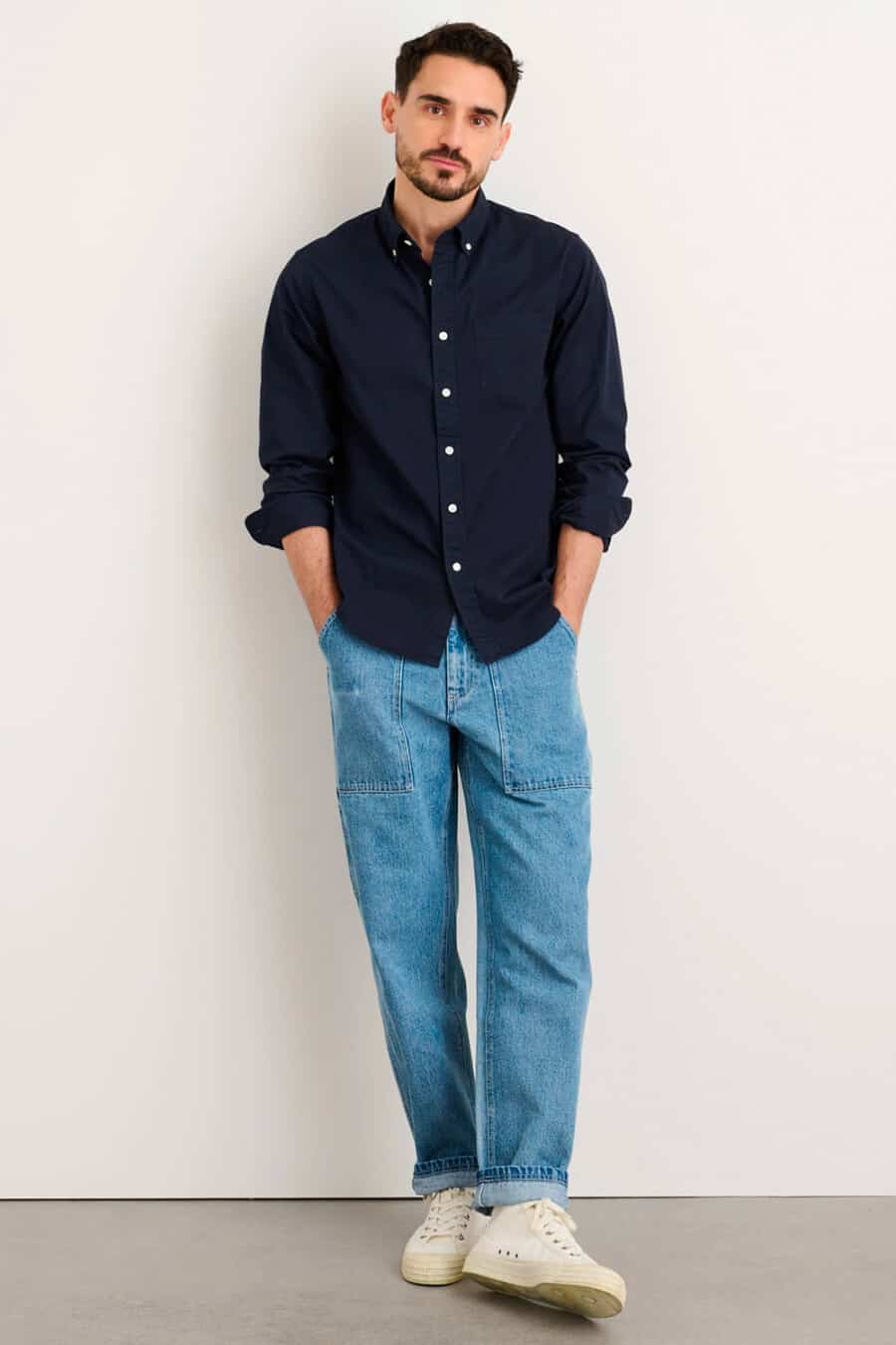 Men's light wash carpenter jeans, navy Oxford button-down shirt and white mid-top canvas sneakers outfit