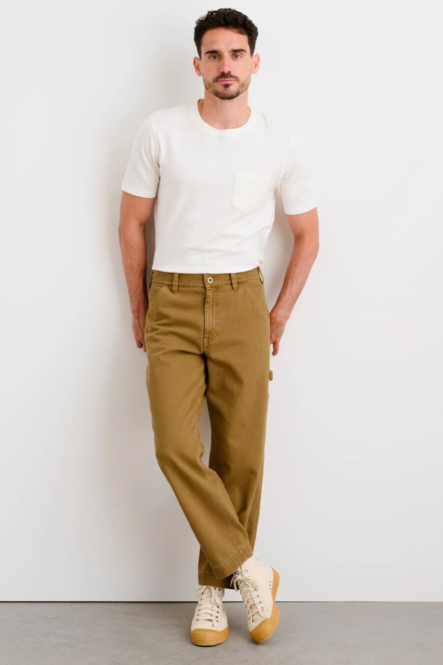 Men's khaki carpenter pants, tucked in white T-shirt and canvas gum sole high-top sneakers outfit