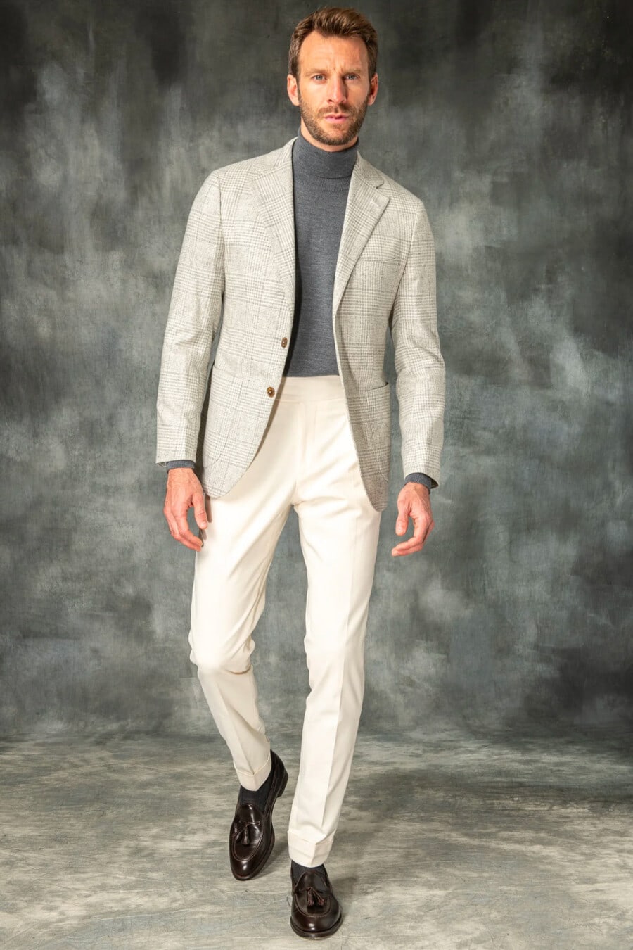 Men's light grey check blazer, mid grey turtleneck, ivory tailored pants, charcoal socks and brown leather tassel loafers outfit