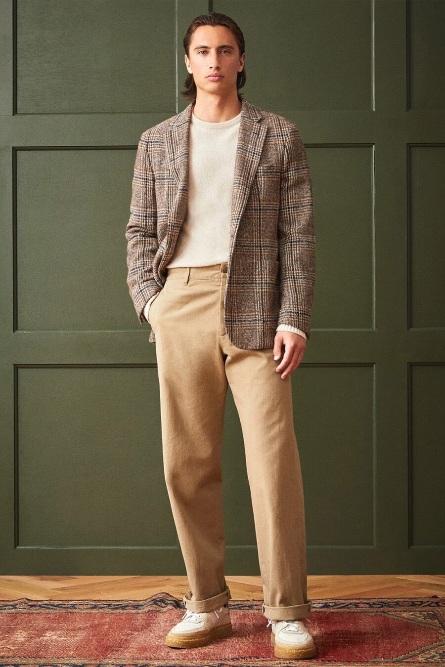 Men's wide-leg khaki chinos, off-white crew neck sweater, brown tweed check blazer and white gum sole sneakers outfit