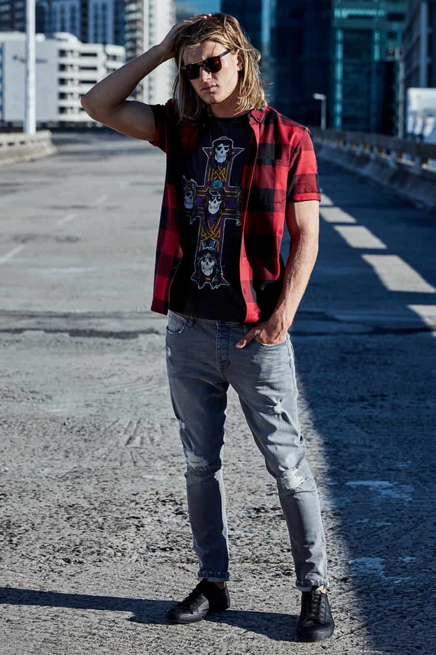 Men's ripped grey jeans, skull print black T-shirt, red/black check short-sleeve shirt left open and black sneakers grunge outfit