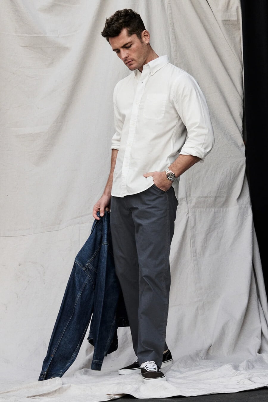 Men's straight navy chinos, white Oxford shirt, denim jacket and black Vans skate shoes outfit