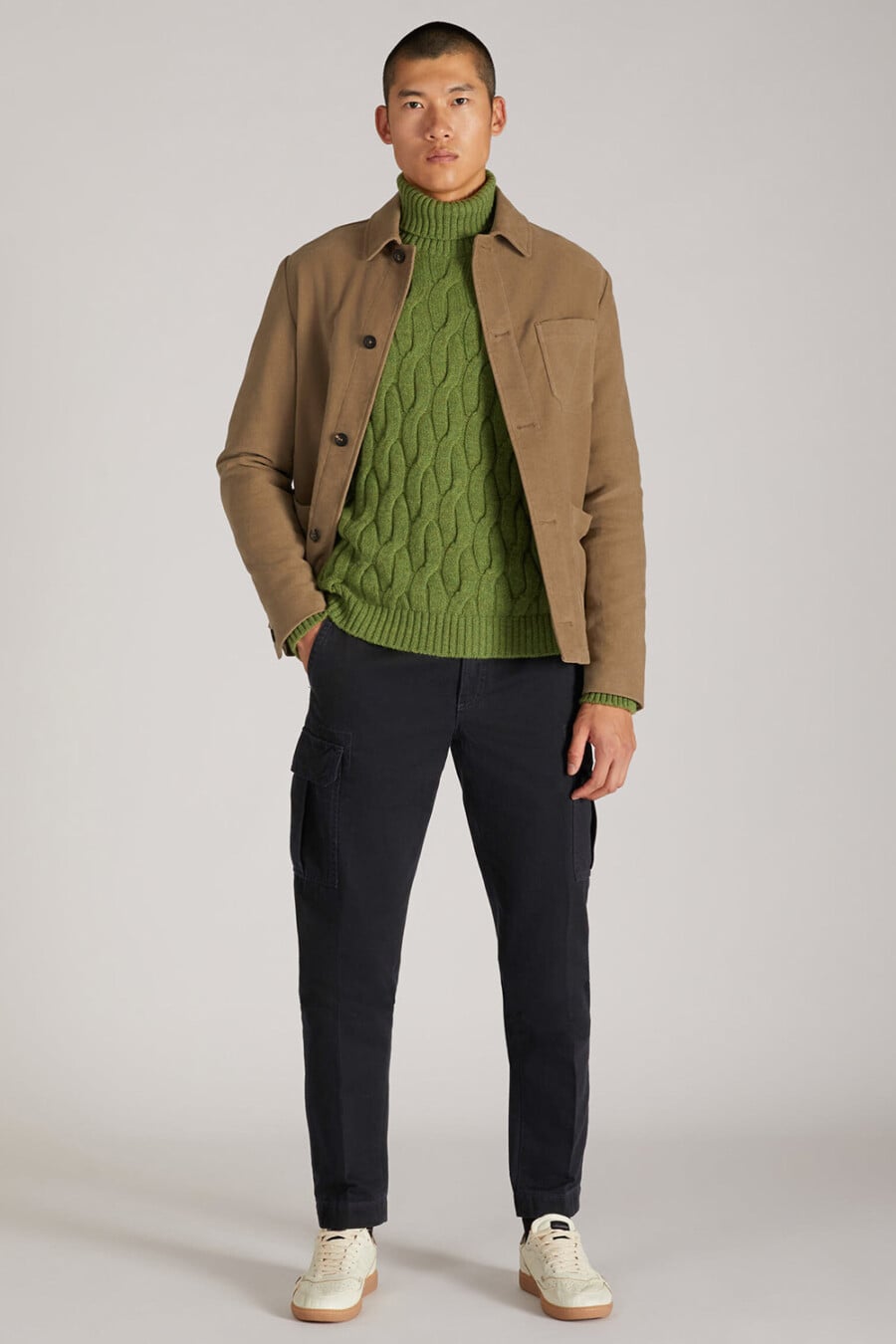 Men's navy cargo pants, green cable knit turtleneck sweater, khaki twill overshirt and off-white gum sole sneakers outfit