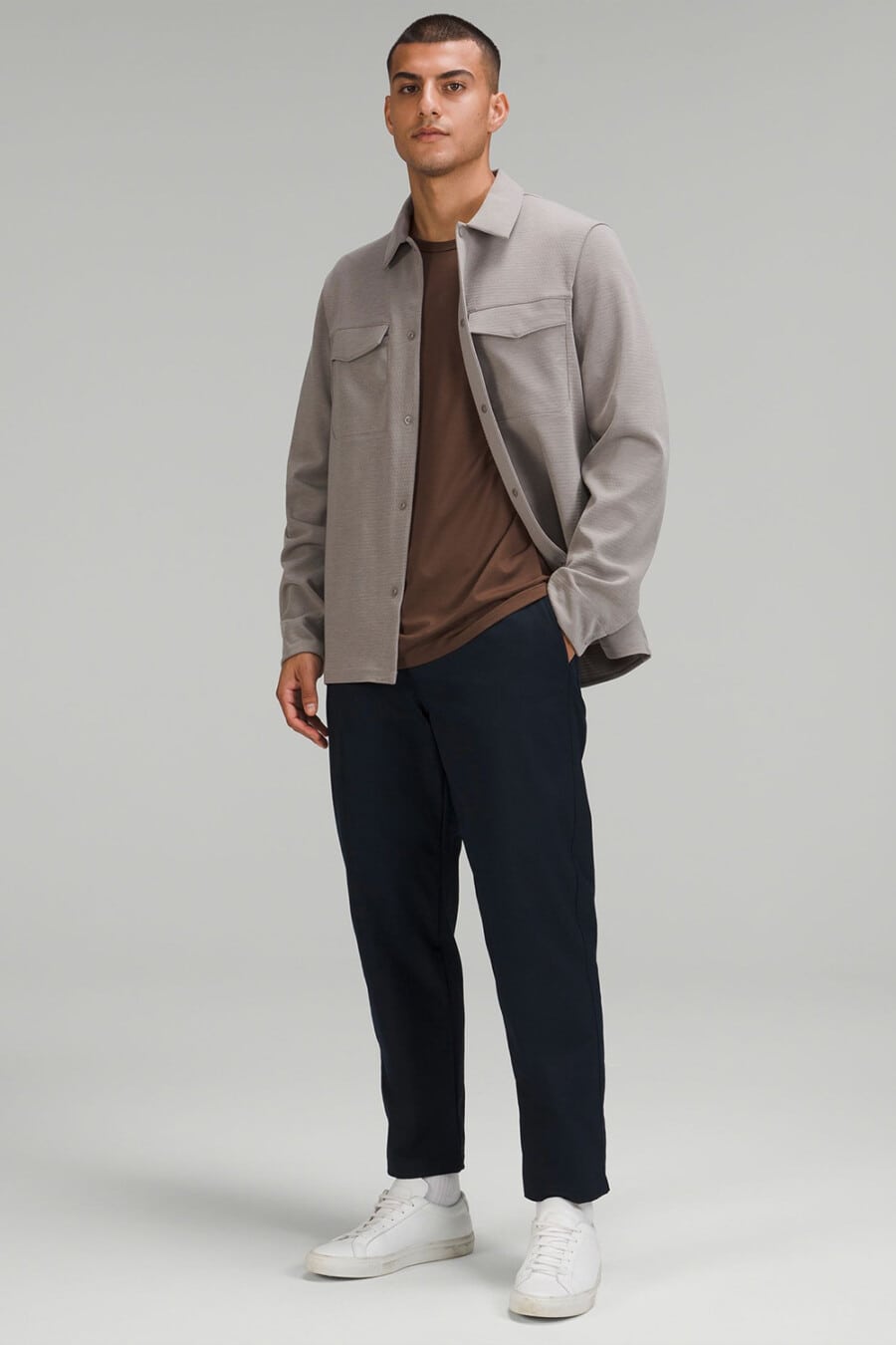 Men's cropped navy pants, brown T-shirt, light brown overshirt, white socks and white sneakers outfit