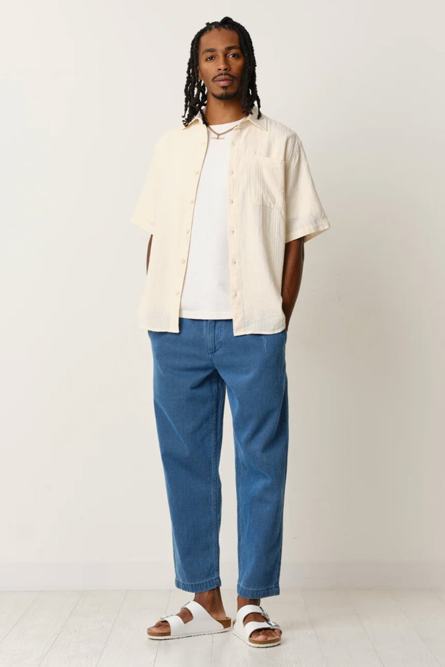 Men's cropped mid blue chinos, white T-shirt, cream short-sleeve shirt and white leather slider sandals outfit