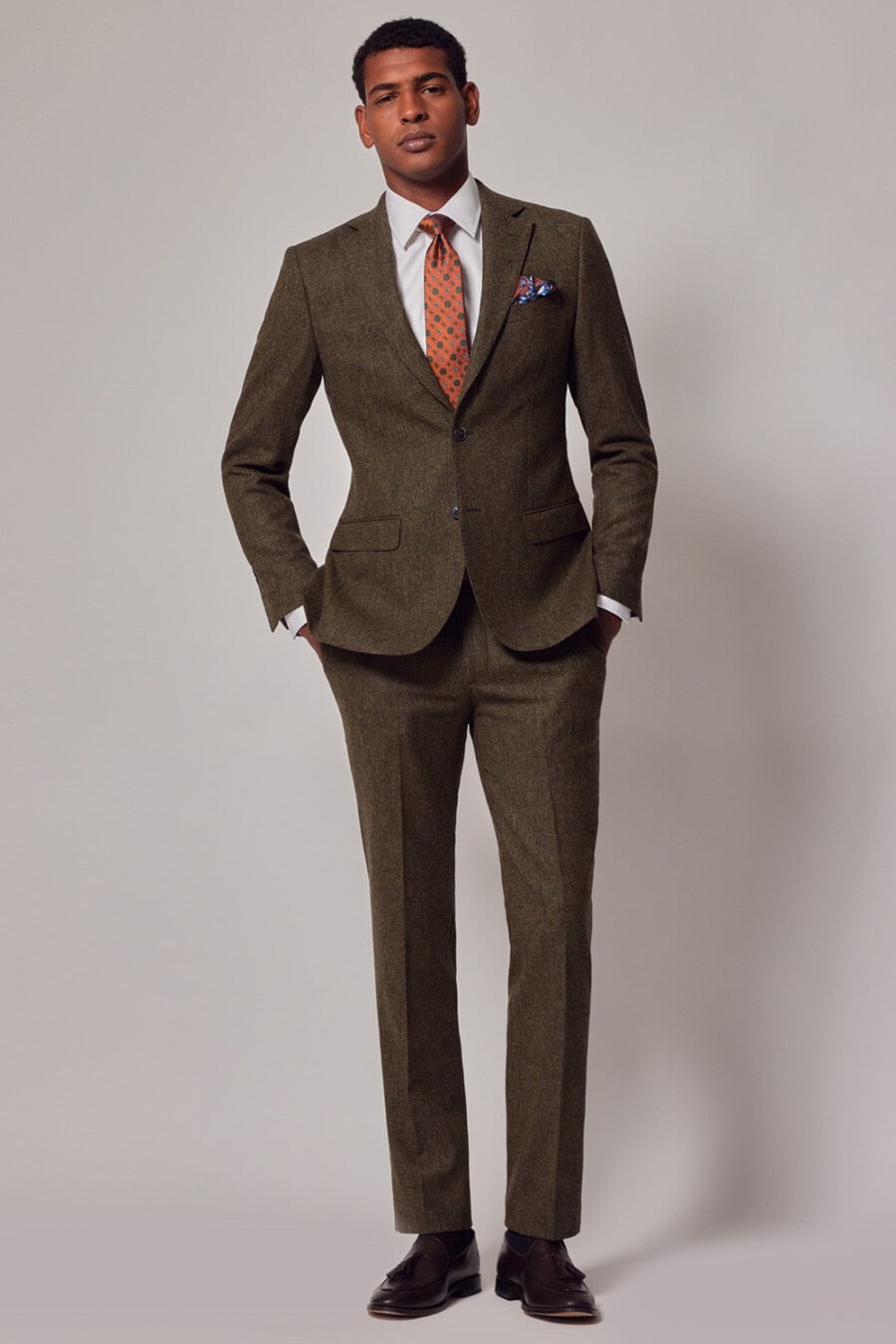 Men's green tweed suit, white shirt, orange tie and brown leather tassel loafers outfit