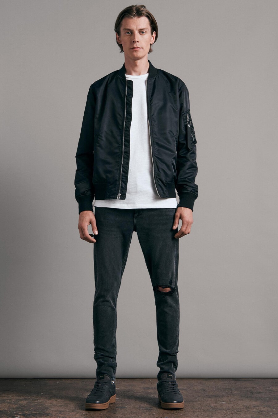 Men's black ripped jeans, white oversized T-shirt, black bomber jacket and black gum sole sneakers outfit