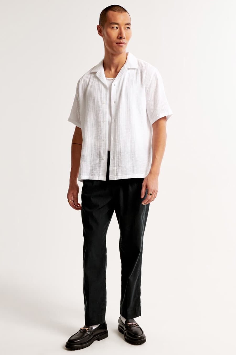 Men's black cropped pants, white tank top, white Camp collar shirt, white socks and black horsebit leather loafers outfit