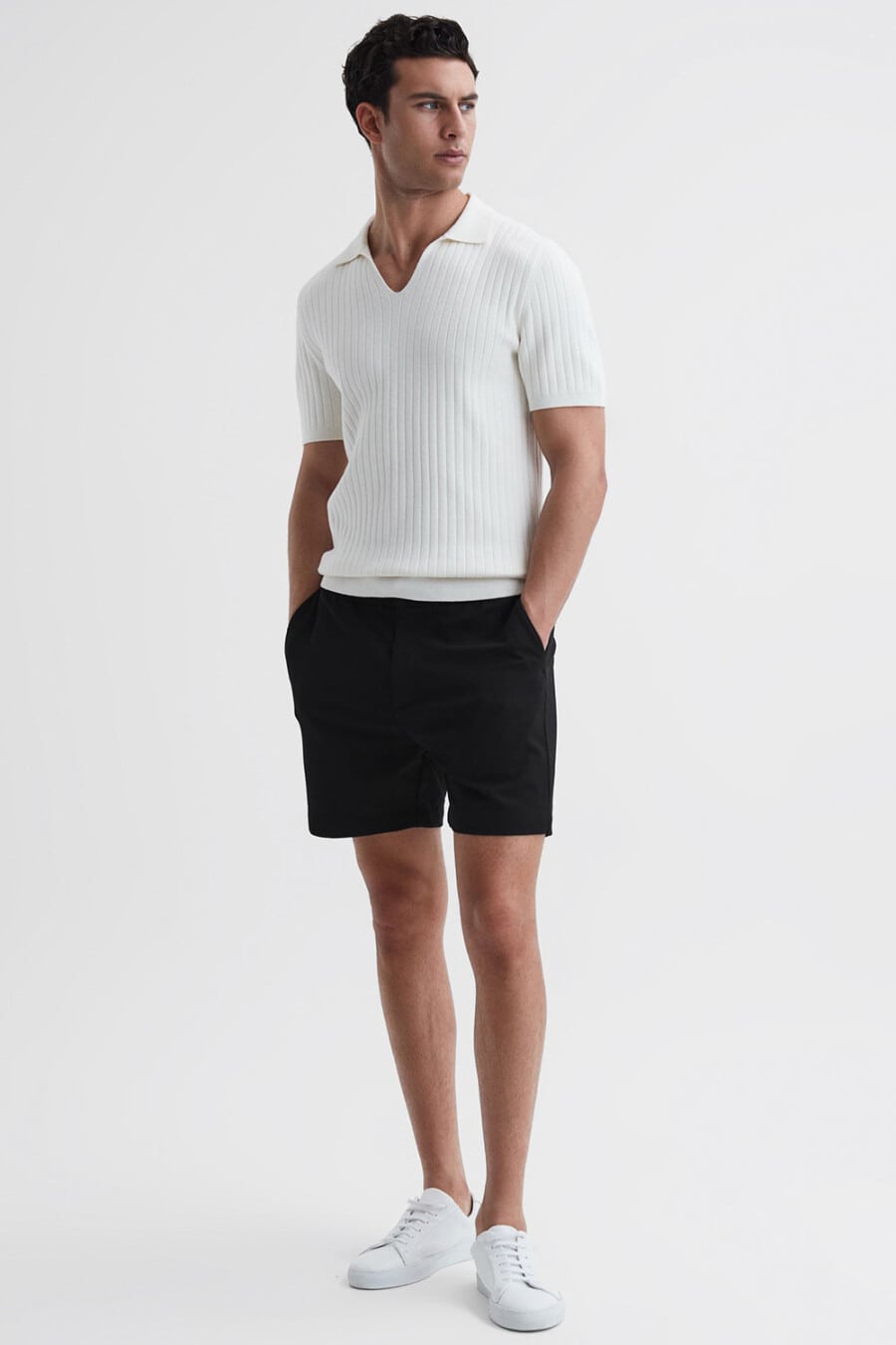 Men's black tailored shorts, white ribbed polo shirt and white sneakers worn sockless outfit