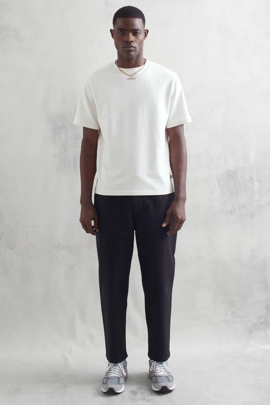 Men's black tapered pants, heavyweight white T-shirt, gold pendant necklace and grey New Balance sneakers outfit