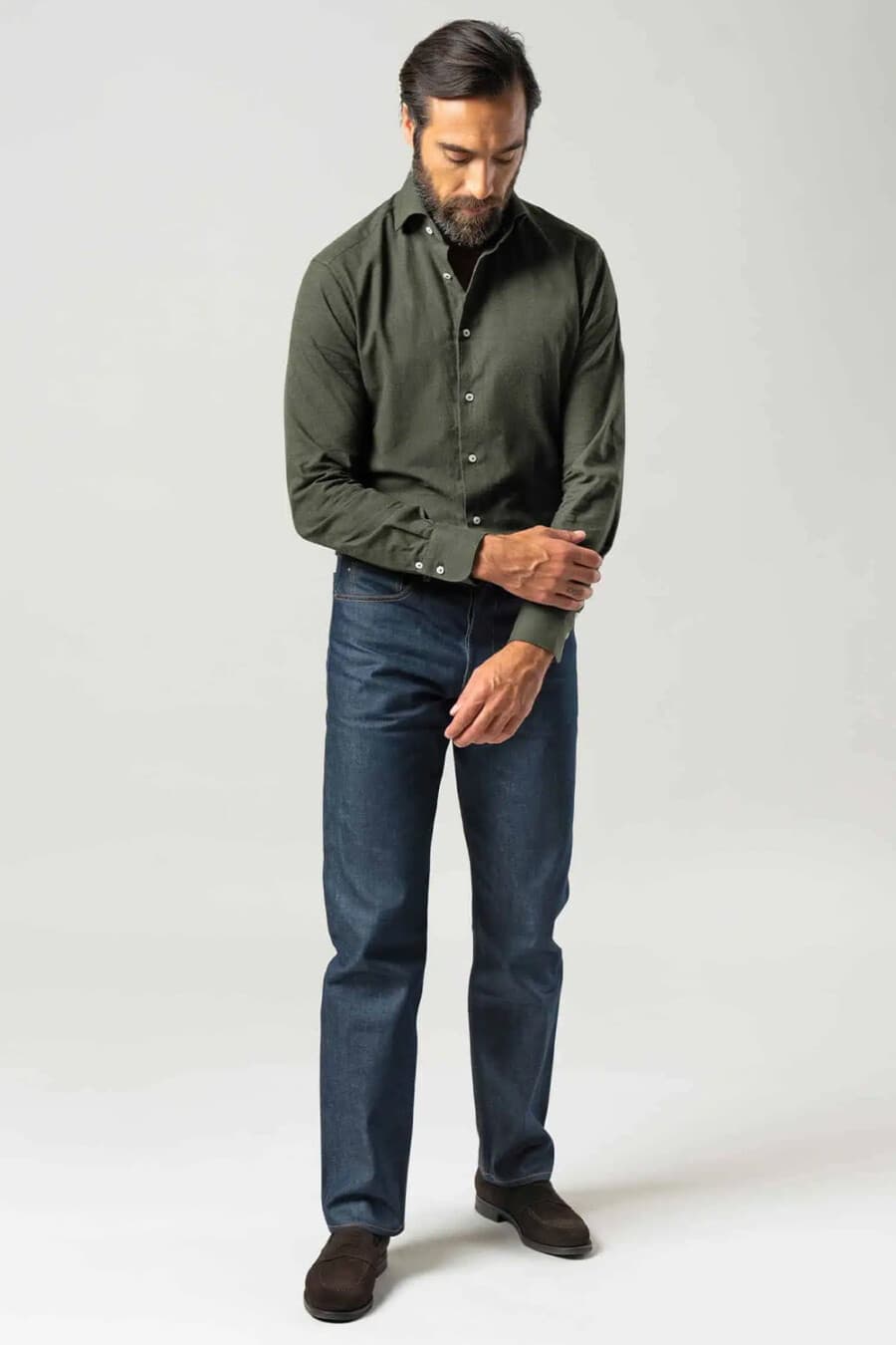 Men's dark raw denim jeans, tucked in green dress shirt and brown suede shoes outfit