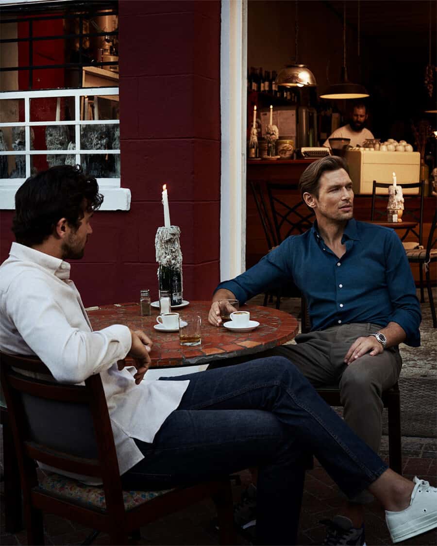 Two men wearing dress shirts with jeans having coffee