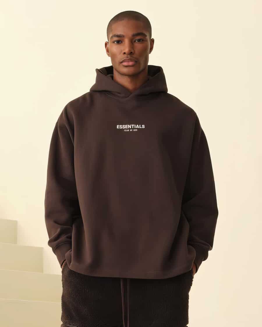 Man wearing black Fear of God Essentials oversized hoodie with wide black pants