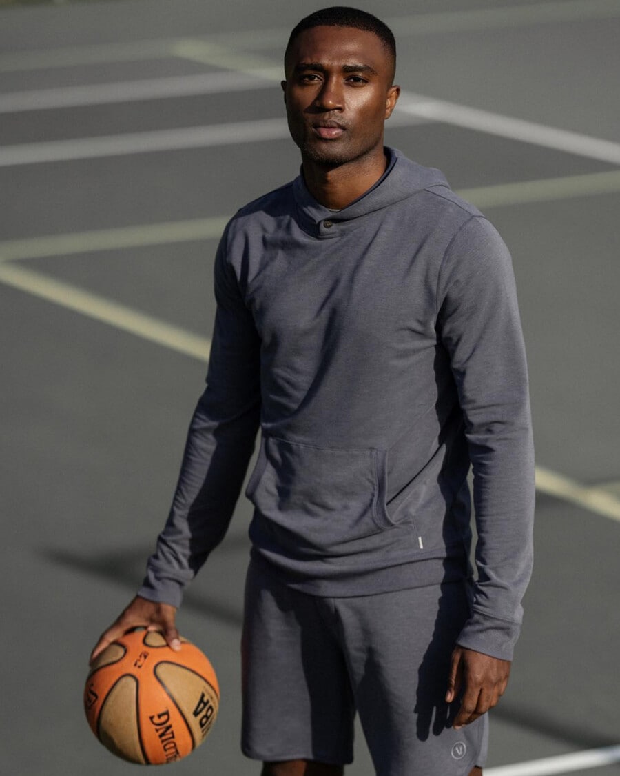 Man in matching shorts and performance hoodie by Vuori holding a basketball