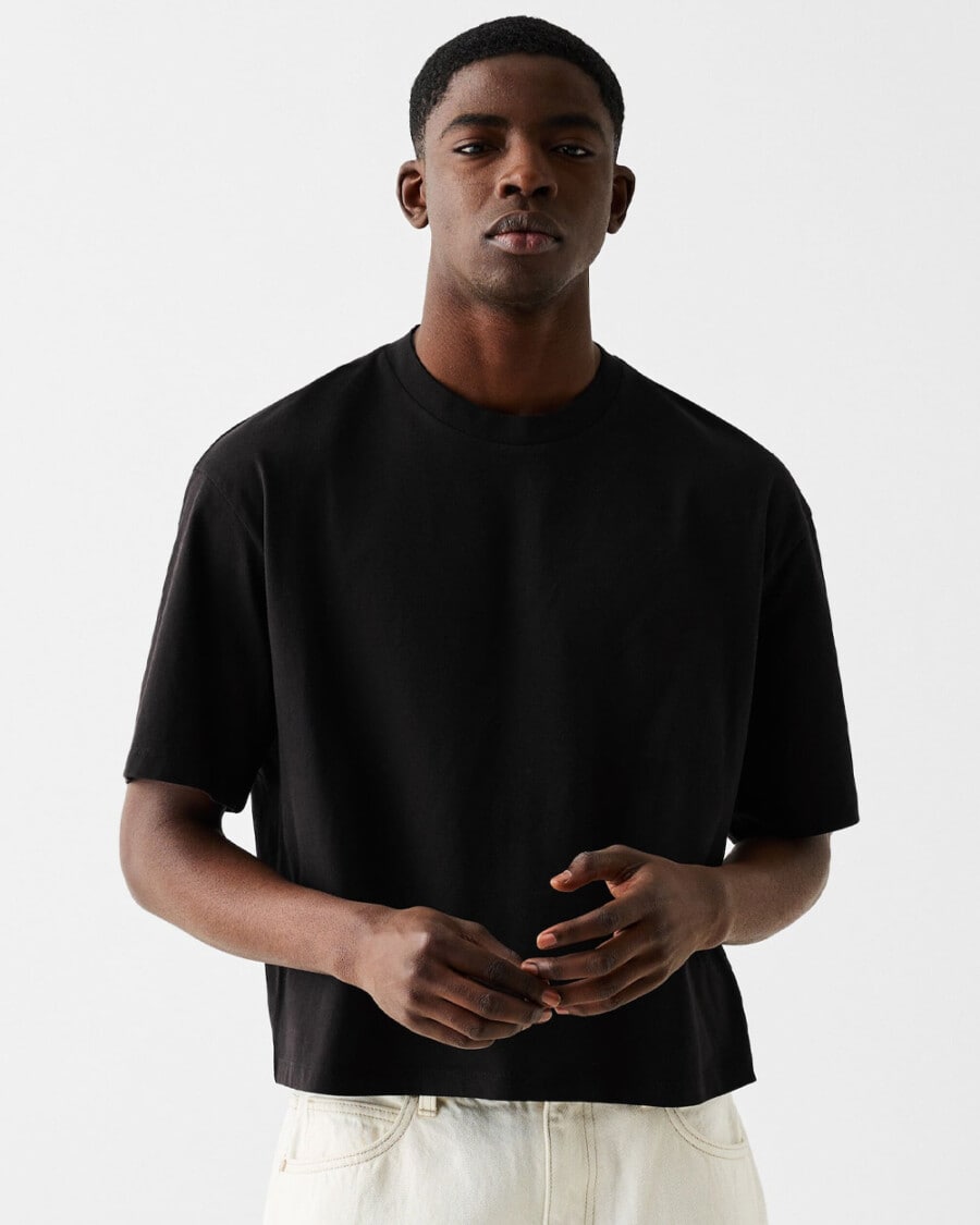 Men's T-shirt trend - man wearing a short boxy black T-shirt with white jeans