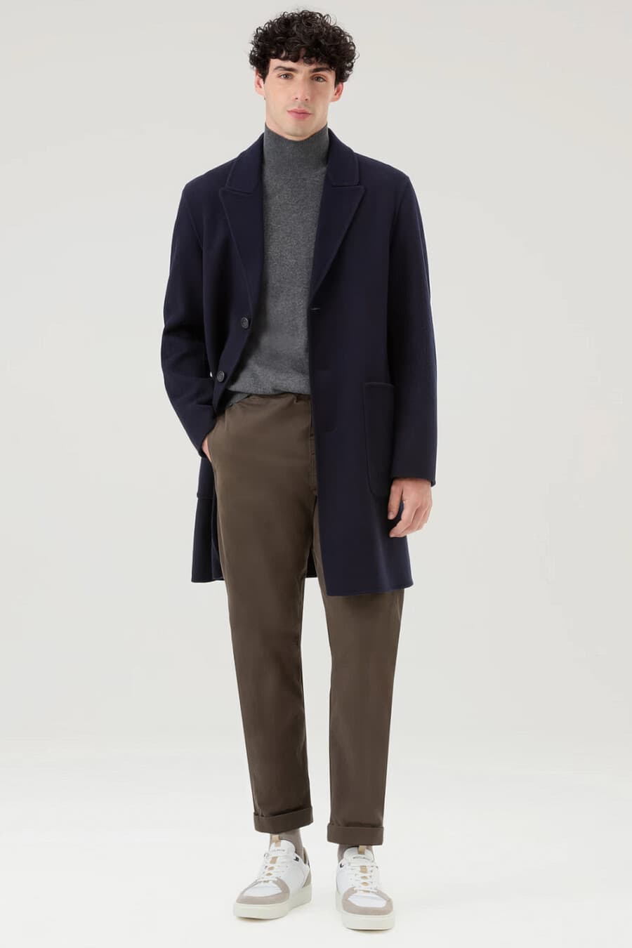 Men's brown pants, grey turtleneck, navy overcoat and white chunky sneakers outfit