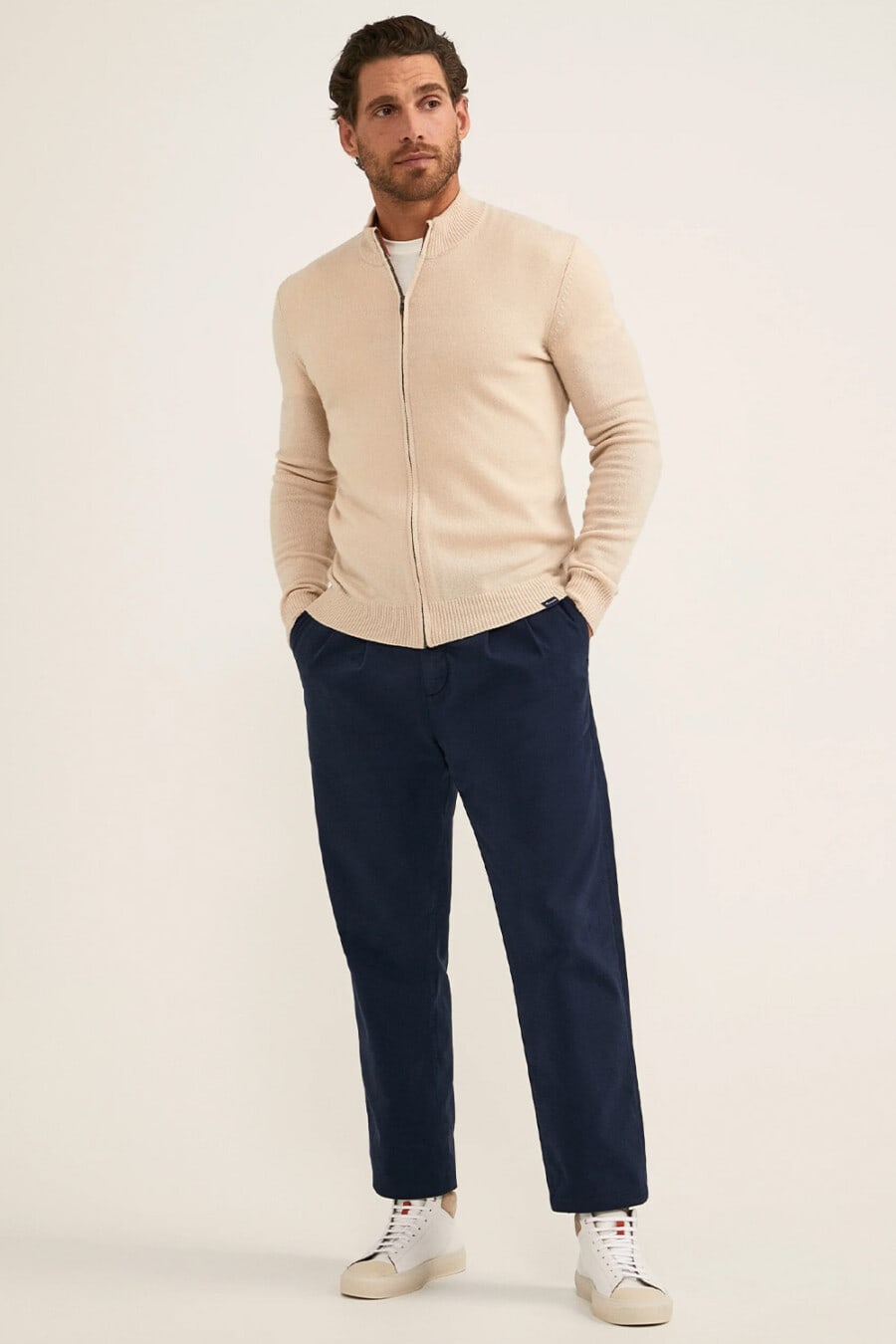 Men's navy cropped pants, white T-shirt, beige zip-up cardigan and white high-top sneakers outfit